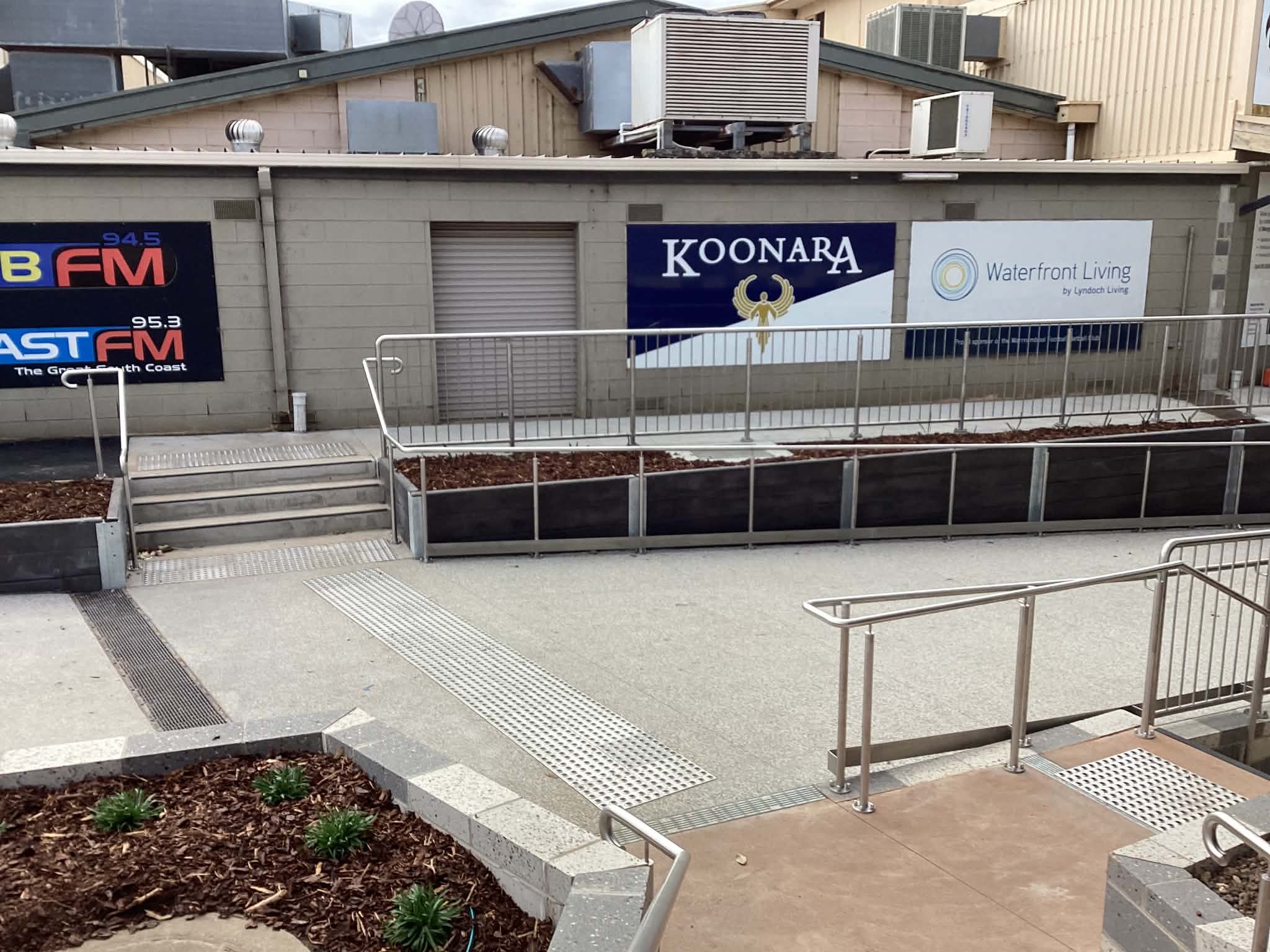 Long stainless steel public access railing beside commercial signage