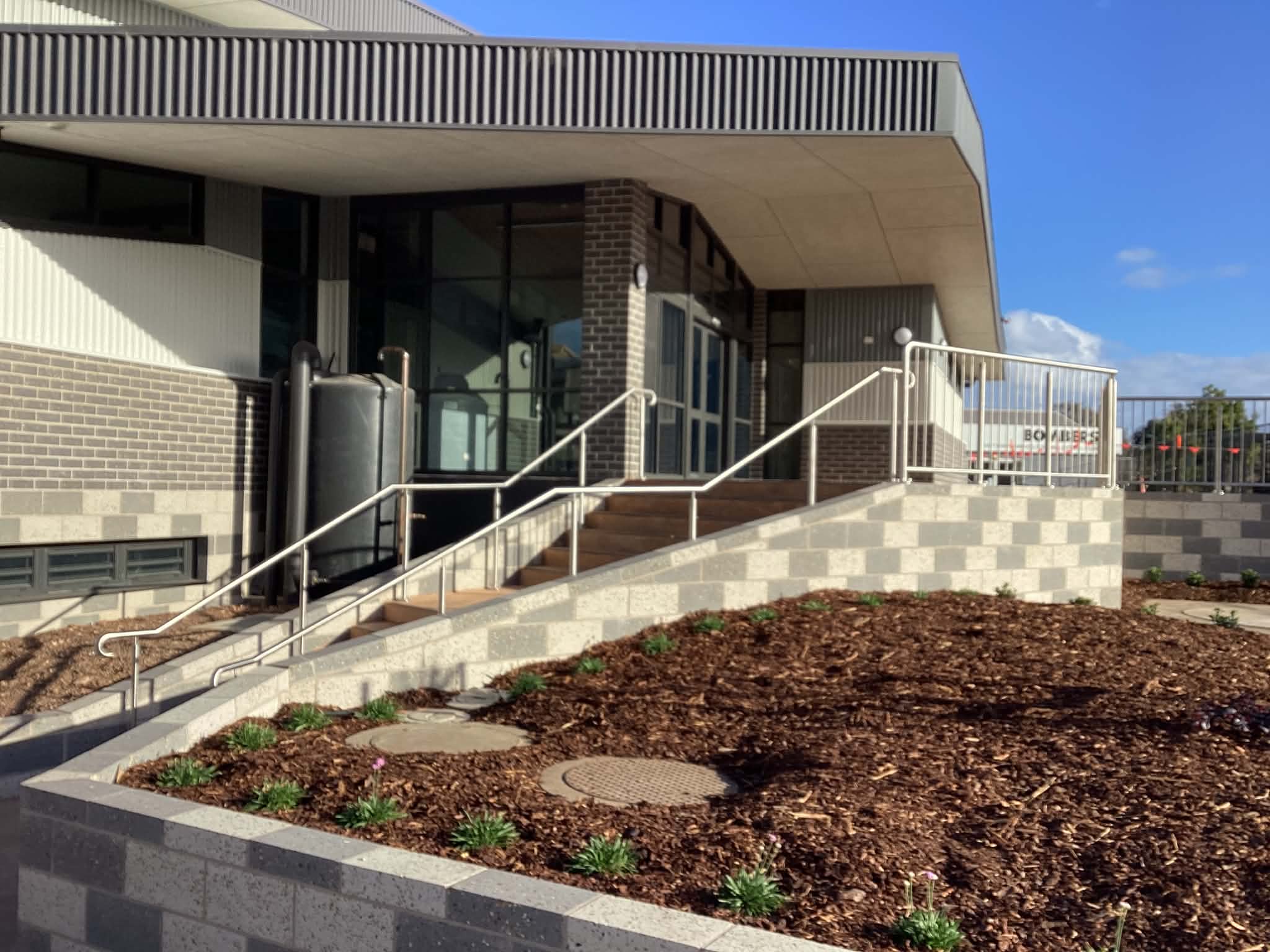 Stainless steel handrails installed on an accessible entrance ramp outside a commercial building