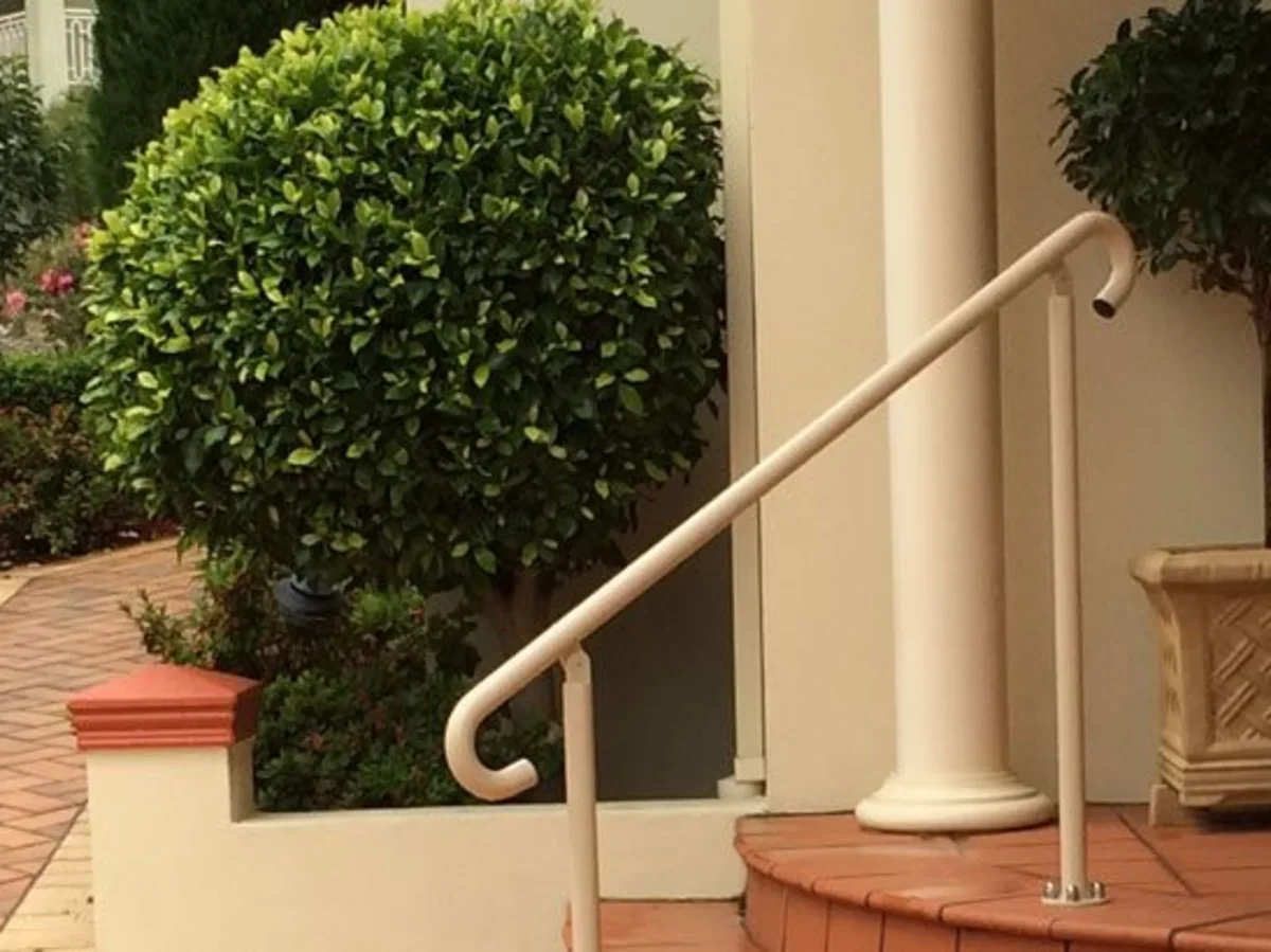Cream home handrail installed beside an entrance path and steps