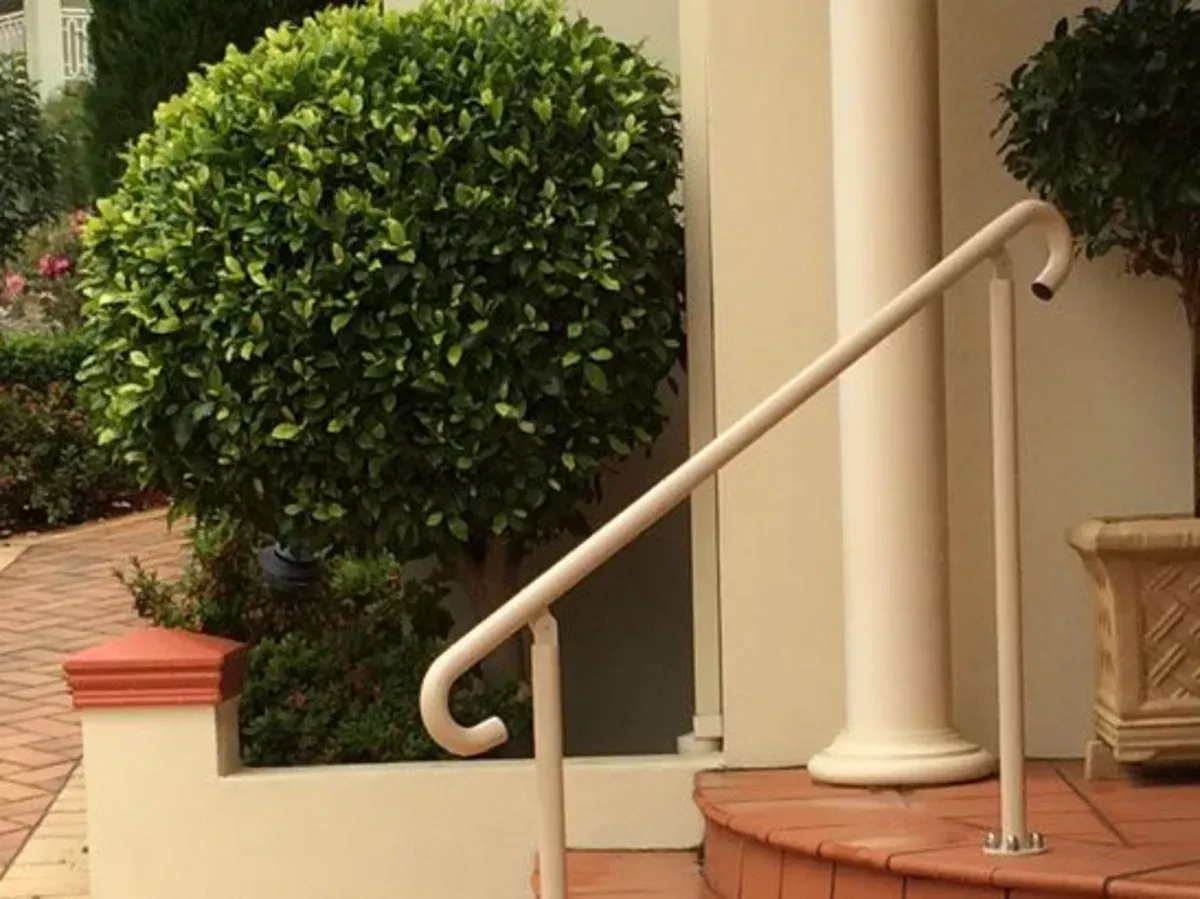 Cream home handrail installed beside an entrance path and steps